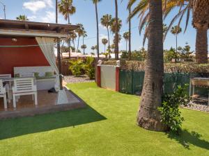 a backyard with a lawn with a table and a tree at Tunos 83 in Maspalomas