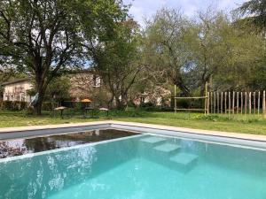 a swimming pool in front of a yard with trees at DameChouette in Pujols Gironde