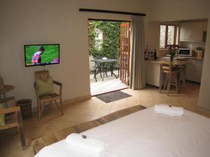 a living room with a bed and a tv on the wall at Apple Cottages in George
