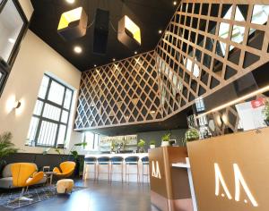 a restaurant with a bar with yellow chairs at Le Magic Hôtel & Spa in Vitré