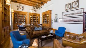 a living room with leather couches and blue chairs at Drostdy Hotel in Graaff-Reinet