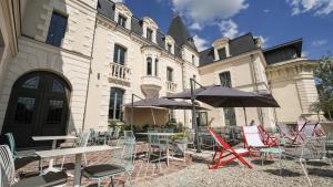 a group of chairs and tables and umbrellas in front of a building at Le Magic Hôtel & Spa - Centre Historique - Climatisation - Parking - Bornes de recharge in Vitré