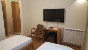 a room with a desk with a television on the wall at Villa Luxury Rooms - Wine Resort in Smederevo