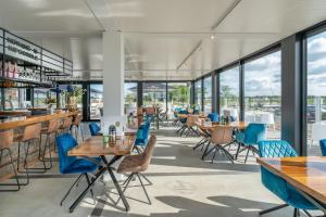 a restaurant with blue chairs and tables and windows at Hotel Biesbosch in Drimmelen