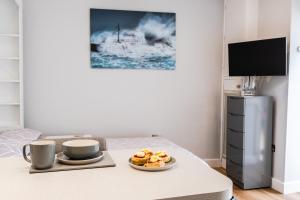 a table with two cups and a plate of food on it at Finest Retreats - The Hideaway - Studio Apartment in Porthleven in Porthleven