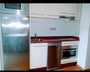 a kitchen with white cabinets and a stainless steel refrigerator at El Camarote del Fraga Apartamento en pleno centro de Vigo con parking in Vigo +11 photos