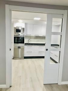 una cocina con armarios blancos y electrodomésticos de acero inoxidable en Apartamento Muralla, en Lugo