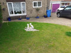 two white statues sitting in the grass in a yard at Dormitory, carpeted garage, Netflix TV, Coffee, tea & sleep 3 easily in Poole