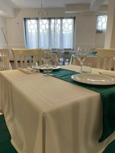 una mesa con mantel blanco y copas de vino en Oasi Park Hotel, en Mascali