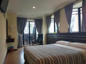 a bedroom with a bed and a chair and windows at Hong Kong Hotel in Brinchang