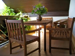 Ferienwohnung im DG, Parkplatz vorm Haus, WLAN في Bielatal: طاولة خشبية مع كرسيين و مزهرية بها ورد