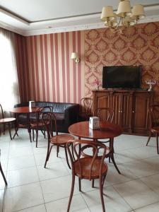 a living room with tables and chairs and a tv at Shelter Hotel & Restaurant in Kolodezhno