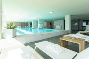 a large swimming pool with white furniture in a building at Valarin Luxury Apartments & Wellness, Vercana by Rent All Como in Vercana