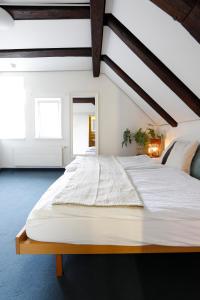 - une chambre mansardée avec un grand lit blanc dans l'établissement Hotel Untertor - 24H Self Check-in, à Altstätten
