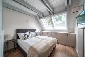 ein Schlafzimmer mit einem großen Bett in einem Zimmer mit Fenstern in der Unterkunft Domizil am Ostseewald - Haus Zaunwinde in Zingst