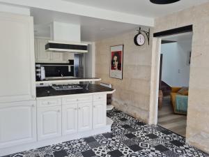 a kitchen with white cabinets and a black counter top at Maison de Campagne cosy in Pons