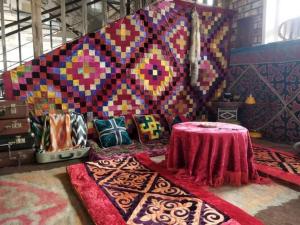 Habitación con mesa y pared colorida con alfombras. en Olive Ala-Archa Hotel & SPA, en Verkhnyaya Alaarcha