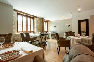 uma sala de jantar com mesas, cadeiras e janelas em Grand Hotel Don Gregorio em Salamanca