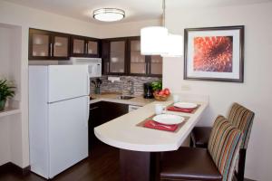 a kitchen with a white refrigerator and a table at Sonesta ES Suites Atlanta Alpharetta Avalon in Alpharetta