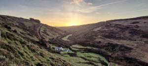 vistas a un valle con una casa en una colina en Darracott Farm Cottage, en Welcombe