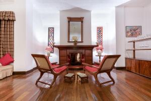 ein Wohnzimmer mit 2 Stühlen und einem Kamin in der Unterkunft Scottish Planter Bungalow- Thema Collection in Nuwara Eliya
