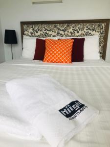 Hiigh Apartments في ملبورن: سرير مع بطانية بيضاء ومخدات برتقالية