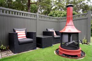 a fireplace in a yard with chairs and a fence at Elegant bluestone cottage located at the Red Hill Peony Estate in Red Hill