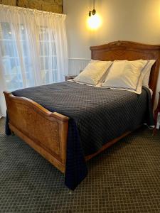 a bedroom with a large wooden bed with white pillows at Elegant bluestone cottage located at the Red Hill Peony Estate in Red Hill