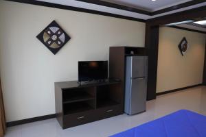 a room with a refrigerator and a tv on a wall at THOMLEK Guesthouse in Cha Am