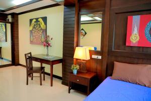 ein Schlafzimmer mit einem Bett und einem Schreibtisch mit einer Lampe in der Unterkunft THOMLEK Guesthouse in Cha-am