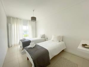 a white bedroom with two beds and a window at CC - Casa da Costa in Costa Nova