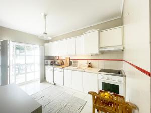 a kitchen with white cabinets and a sink and a table at CC - Casa da Costa in Costa Nova