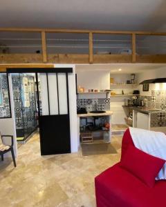 a living room with a red couch and a kitchen at Les Remparts de Lauris Coeur Médiéval et Patio in Lauris