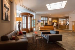 uma sala de estar com sofás e uma pessoa a andar ao fundo em Arenas Resort Schweizerhof em Sils Maria