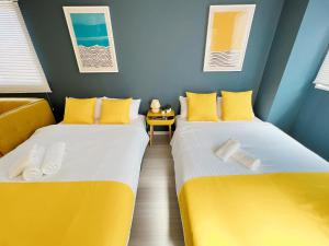 2 camas en una habitación de color amarillo y azul en OUCHI HOTEL Nagarekawa with Dogs, en Hiroshima 206 fotos más