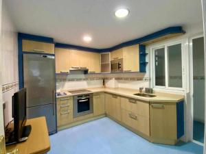 a large kitchen with wooden cabinets and a tv in it at Chicflat Avenida España. Ideal para familias in Estepona