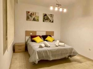 1 dormitorio con 1 cama con almohadas amarillas y rojas en Chicflat Avenida España Ideal para familias, en Estepona