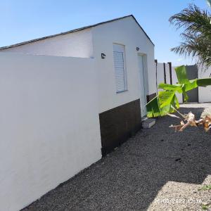 un edificio blanco con una valla y una palmera en Villa Bali con jacuzzi climatizado y piscina climatizada con jacuzzi, en Chiclana de la Frontera