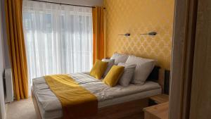 a bedroom with a bed with yellow walls and a window at APARTAMENT ELEGANCE YELLOW w Let's Sea Basen&SPA in Gąski +37 photos