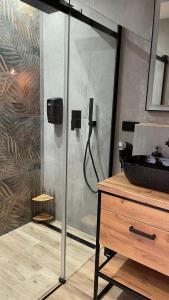 a bathroom with a shower with a sink and a wooden dresser at APARTAMENT ELEGANCE YELLOW w Let's Sea Basen&SPA in Gąski