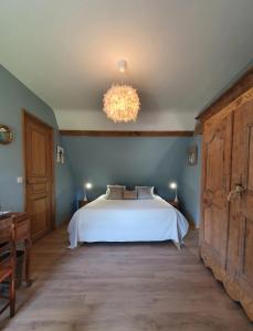 a bedroom with a white bed and a chandelier at LE CLOS JOLY 14 in Saint-Gâtien-des-Bois