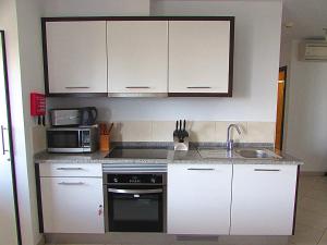 a kitchen with white cabinets and a sink and a microwave at BCV - Private Apartments Dunas Resort 1 & 2 Beds in Santa Maria