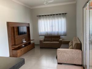 a living room with a couch and a tv at Recanto Asa Delta in Olímpia