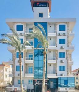 a tall building with palm trees in front of it at El Mena Beach in Ras El Bar