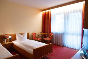 pokój hotelowy z łóżkiem, stołem i oknem w obiekcie Hotel Lorenz w mieście Bad Füssing