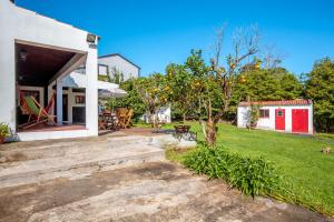 a house with a patio and an orange tree at Quinta dos Reis in Biscoitos