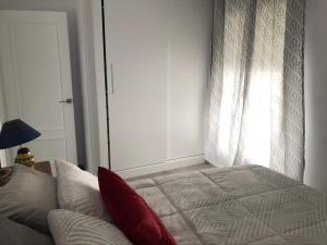 Un dormitorio con una cama con almohadas rojas y una ventana en casa Encarni, balcon de las cuevas, en Setenil