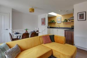 a living room with a yellow couch and a kitchen at Cosy Two Bedroom Coach House - Free Parking for 2 vehicles, WIFI & Netflix in Colchester