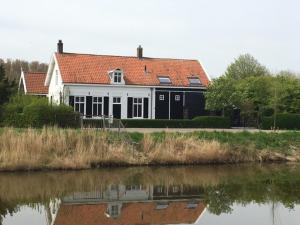 a white house with a red roof next to a river at le Garage in Veere