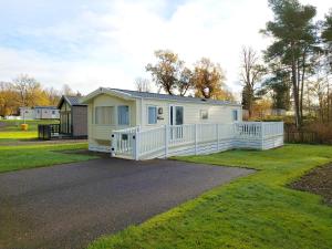 a small white house with a white fence at Callander Woods Holiday Park in Callander